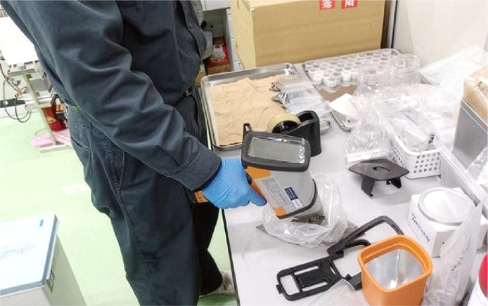 産業廃棄物の処分・再資源化を行う京葉興業の社員がエネルギー分散型蛍光X線分析装置ハンディ型を使って分析している写真